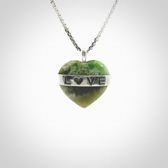 Hand crafted New Zealand jade love heart necklace. This piece has  a sterling silver love written across its' body. This necklace is provided with a sterling silver chain.