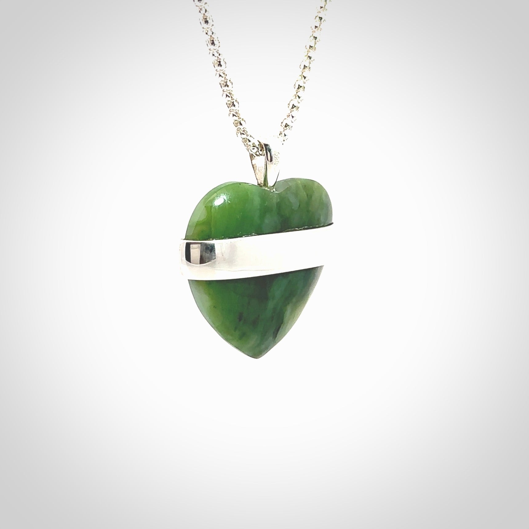 Hand crafted New Zealand jade love heart necklace. This piece has  a sterling silver love written across its' body. This necklace is provided with a sterling silver chain.