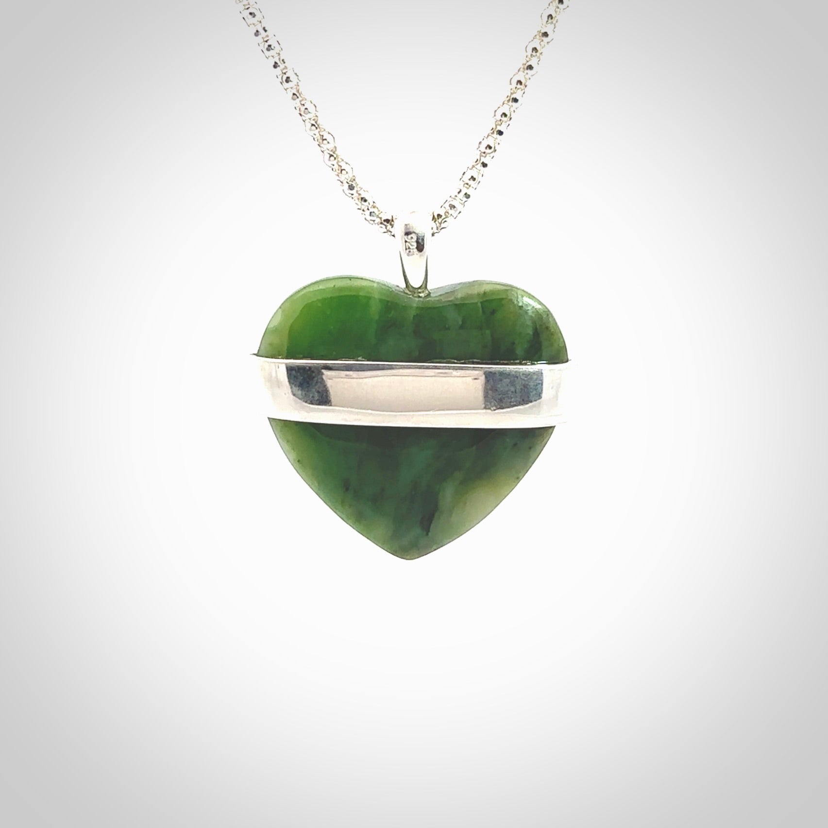 Hand crafted New Zealand jade love heart necklace. This piece has  a sterling silver love written across its' body. This necklace is provided with a sterling silver chain.