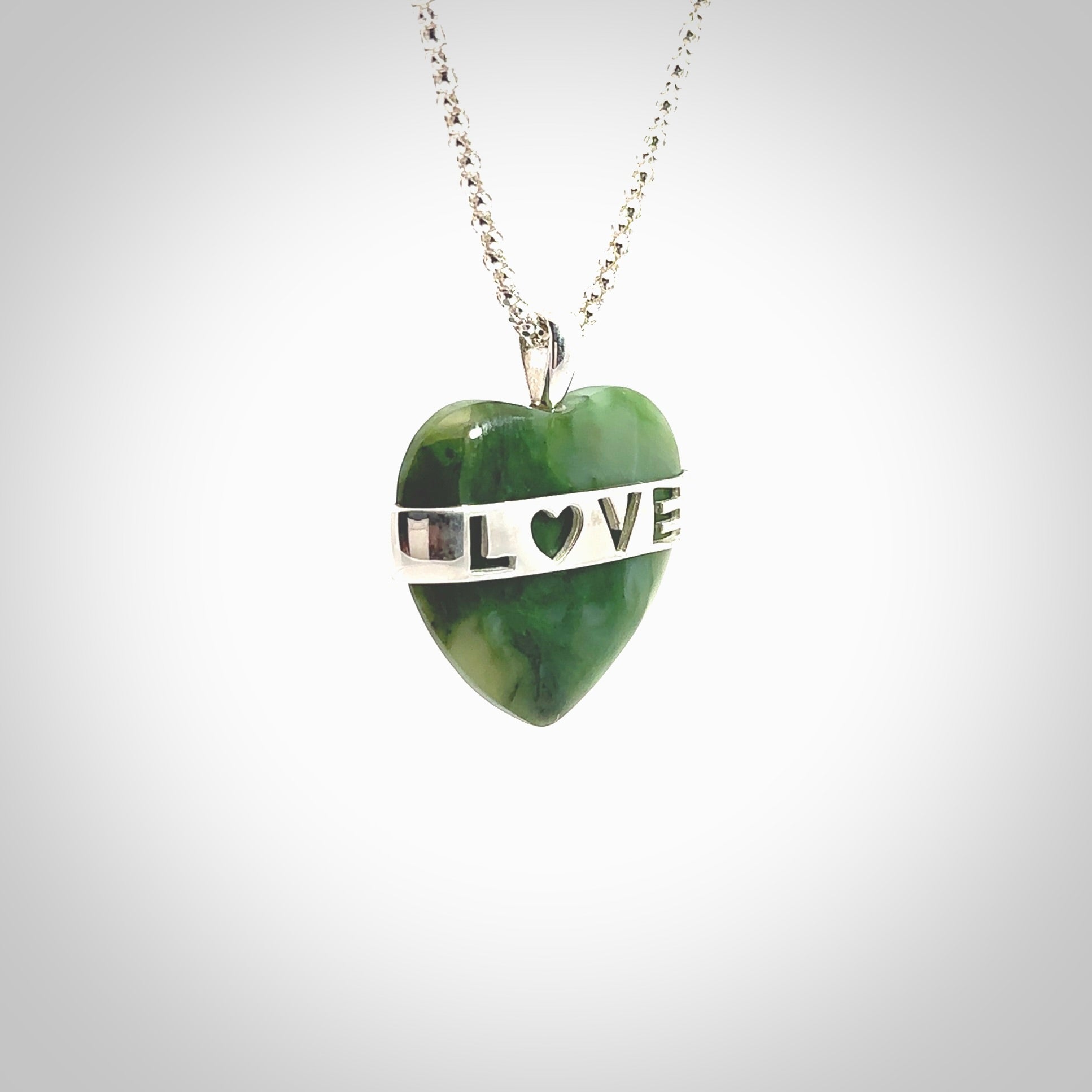 Hand crafted New Zealand jade love heart necklace. This piece has  a sterling silver love written across its' body. This necklace is provided with a sterling silver chain.