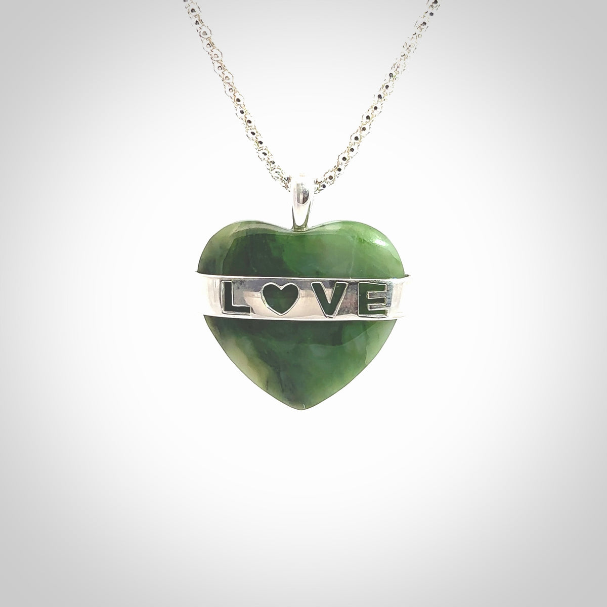 Hand crafted New Zealand jade love heart necklace. This piece has  a sterling silver love written across its' body. This necklace is provided with a sterling silver chain.