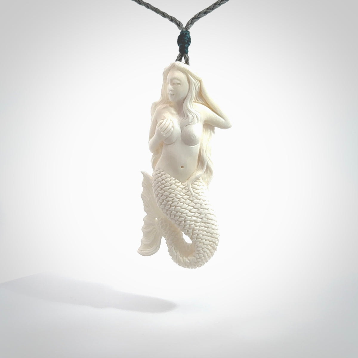 Hand carved large natural bone mermaid pendant. Hand made from real bone. Art to wear. Provided with an adjustable length grey cord and packaged in a woven kete pouch. Bone mermaid necklace.