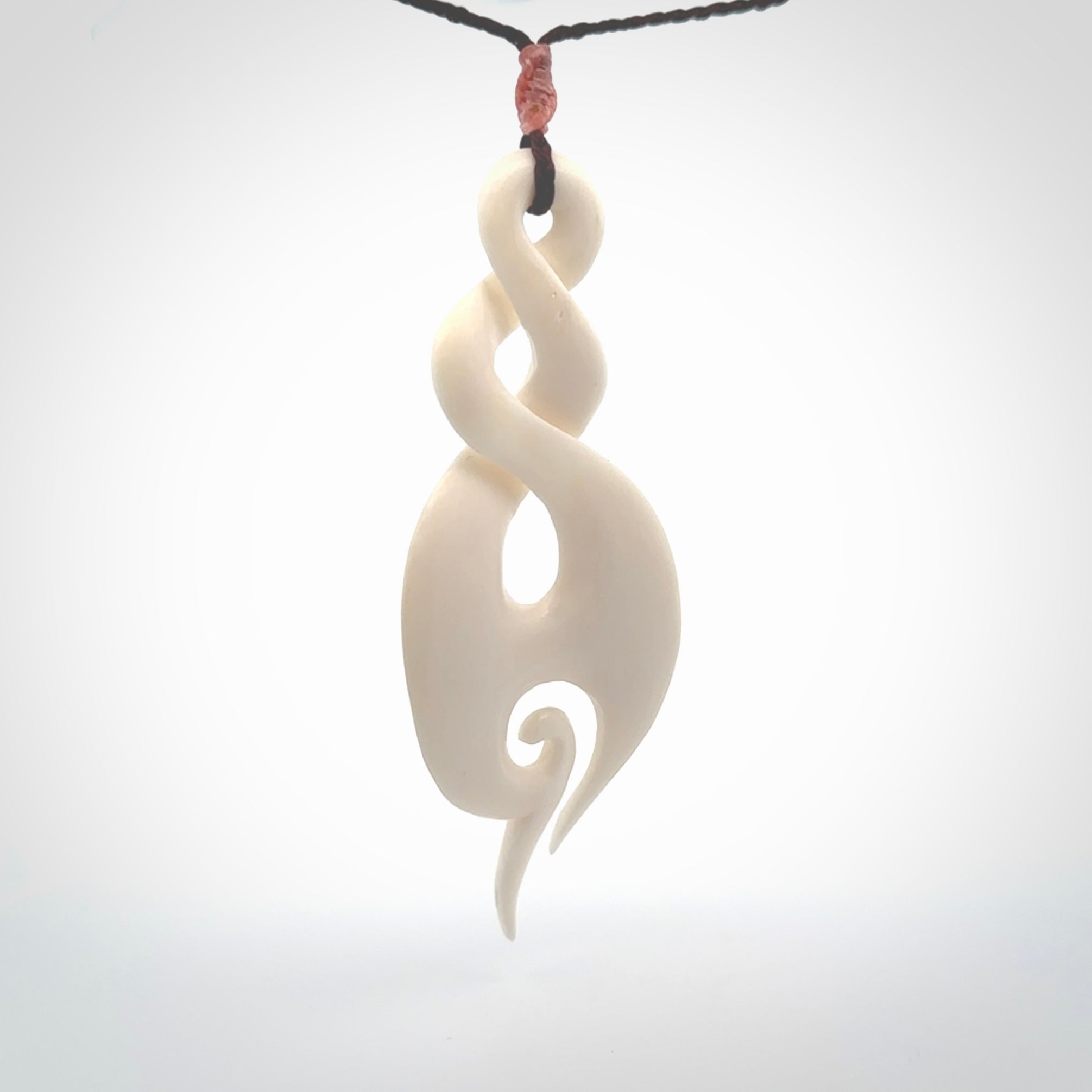 A hand carved large bone twist with koru. A beautiful large double twist pendant carved from bone for NZ Pacific. This is a true piece of wearable art and is provided with an adjustable plum coloured cord.