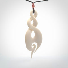 A hand carved large bone twist with koru. A beautiful large double twist pendant carved from bone for NZ Pacific. This is a true piece of wearable art and is provided with an adjustable plum coloured cord.