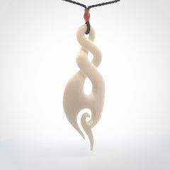 A hand carved large bone twist with koru. A beautiful large double twist pendant carved from bone for NZ Pacific. This is a true piece of wearable art and is provided with an adjustable plum coloured cord.