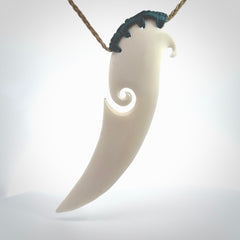 A hand carved large bone drop pendant with koru. A beautiful large drop pendant carved from bone for NZ Pacific. This is a true piece of wearable art and is provided with an adjustable tan coloured cord.