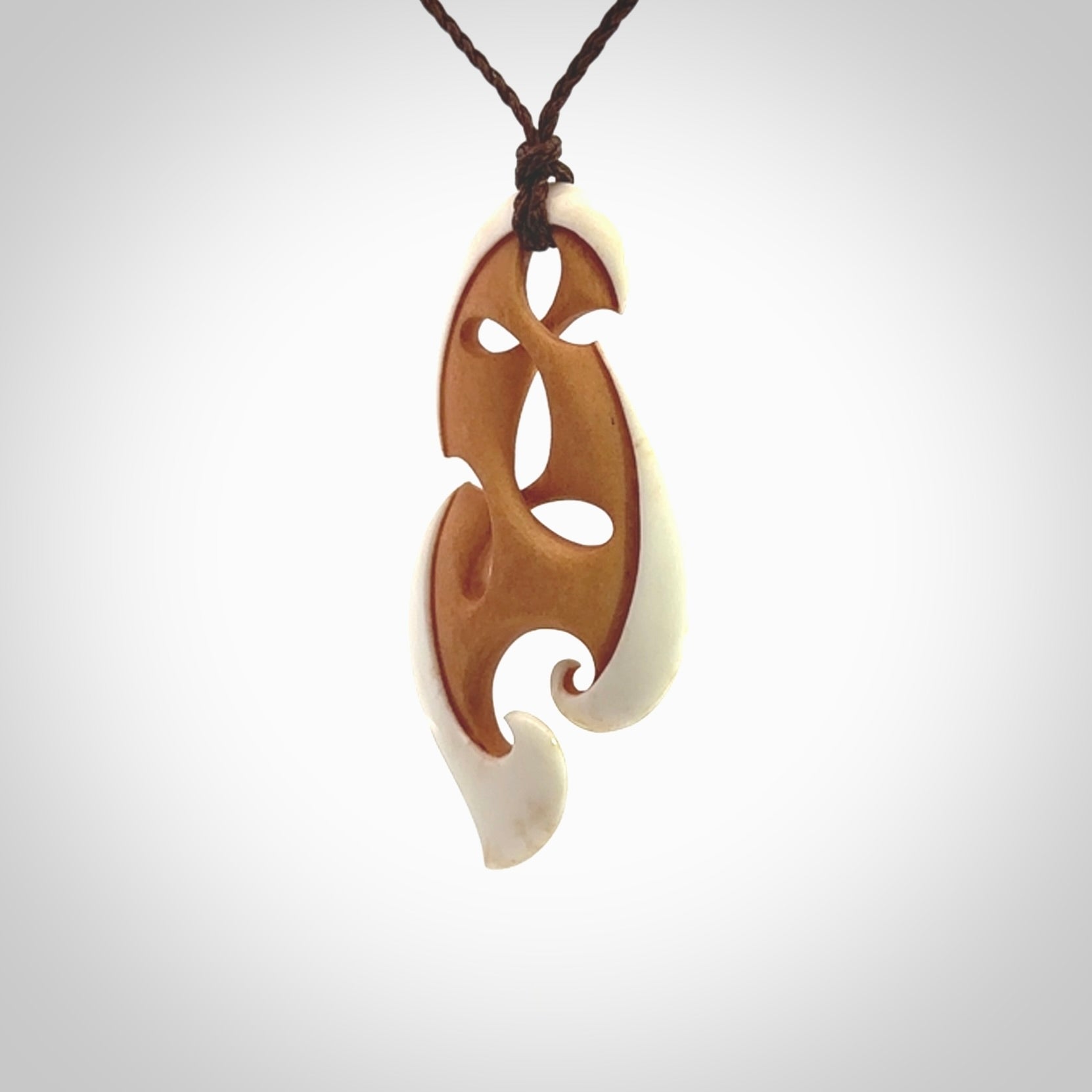 A hand carved bone contemporary, intricate pendant. The cord is a brown colour and is a adjustable in length. A medium-large sized hand made contemporary necklace by New Zealand artist Kerry Thompson. Kerry has stained parts of the bone which really add to the dimension of this pendant. One off work of art to wear.