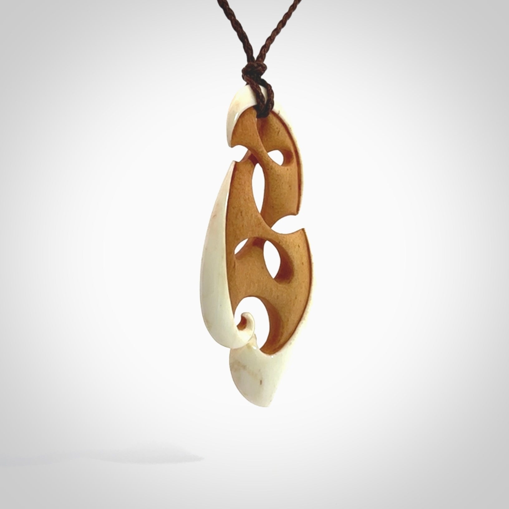 A hand carved bone contemporary, intricate pendant. The cord is a brown colour and is a adjustable in length. A medium-large sized hand made contemporary necklace by New Zealand artist Kerry Thompson. Kerry has stained parts of the bone which really add to the dimension of this pendant. One off work of art to wear.