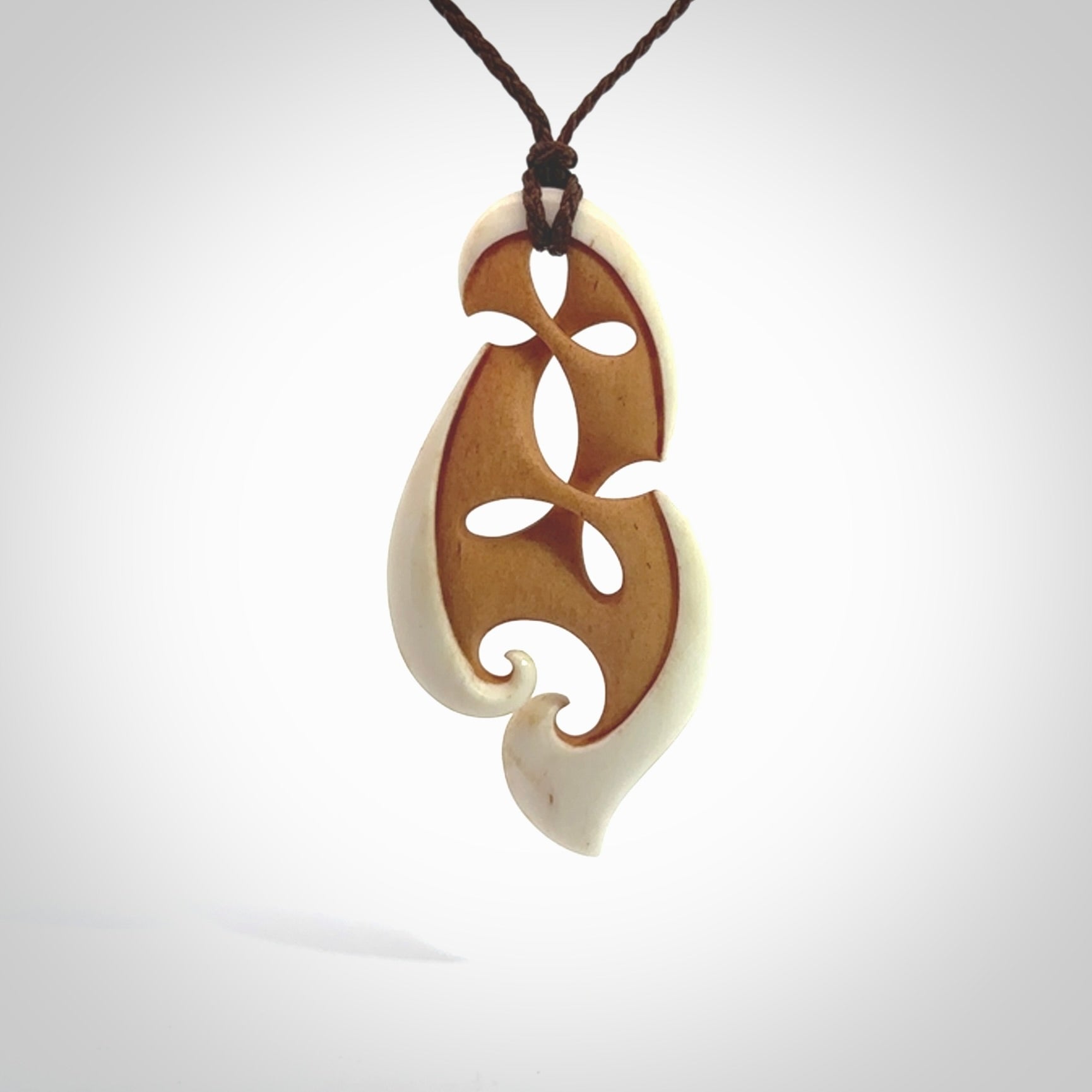 A hand carved bone contemporary, intricate pendant. The cord is a brown colour and is a adjustable in length. A medium-large sized hand made contemporary necklace by New Zealand artist Kerry Thompson. Kerry has stained parts of the bone which really add to the dimension of this pendant. One off work of art to wear.