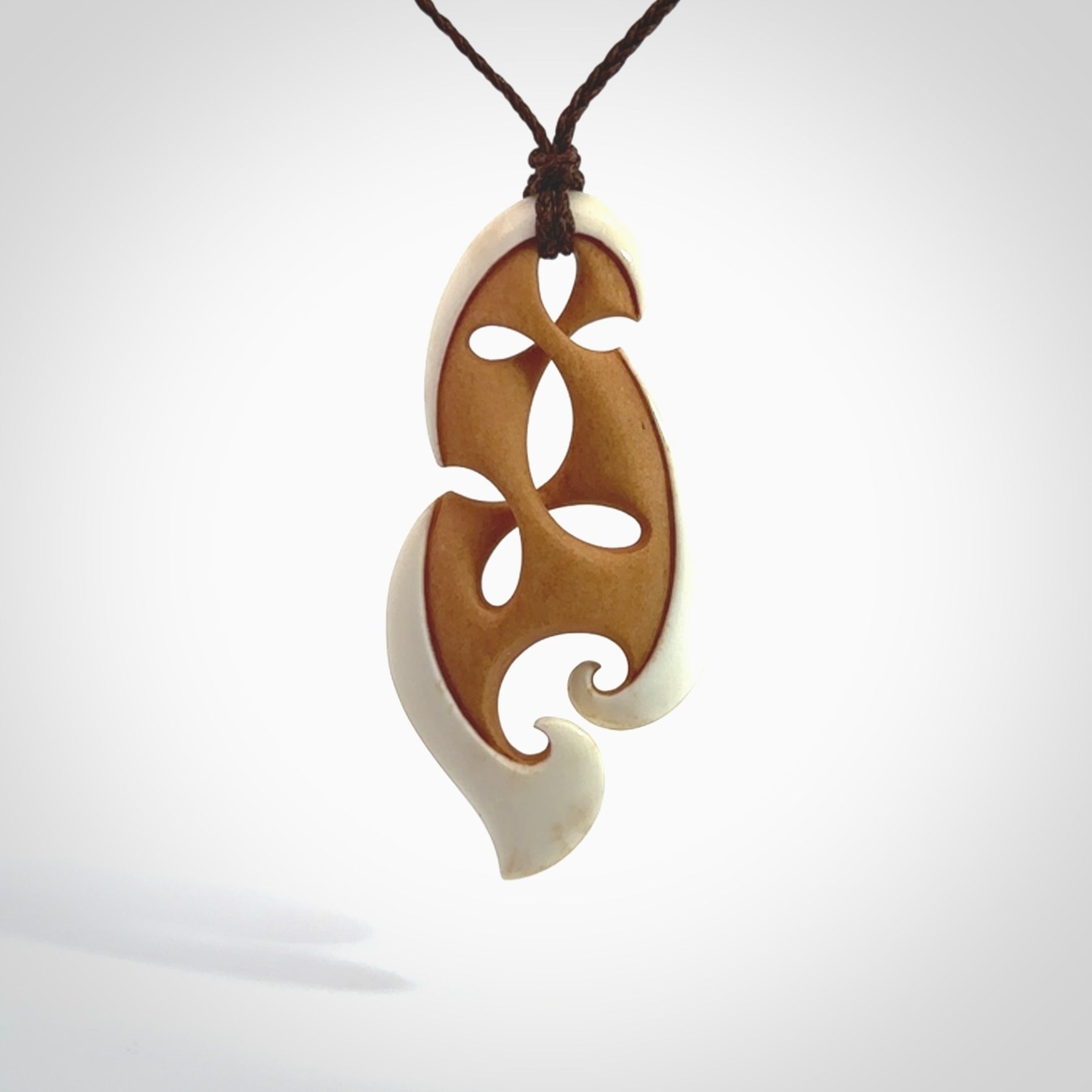 A hand carved bone contemporary, intricate pendant. The cord is a brown colour and is a adjustable in length. A medium-large sized hand made contemporary necklace by New Zealand artist Kerry Thompson. Kerry has stained parts of the bone which really add to the dimension of this pendant. One off work of art to wear.