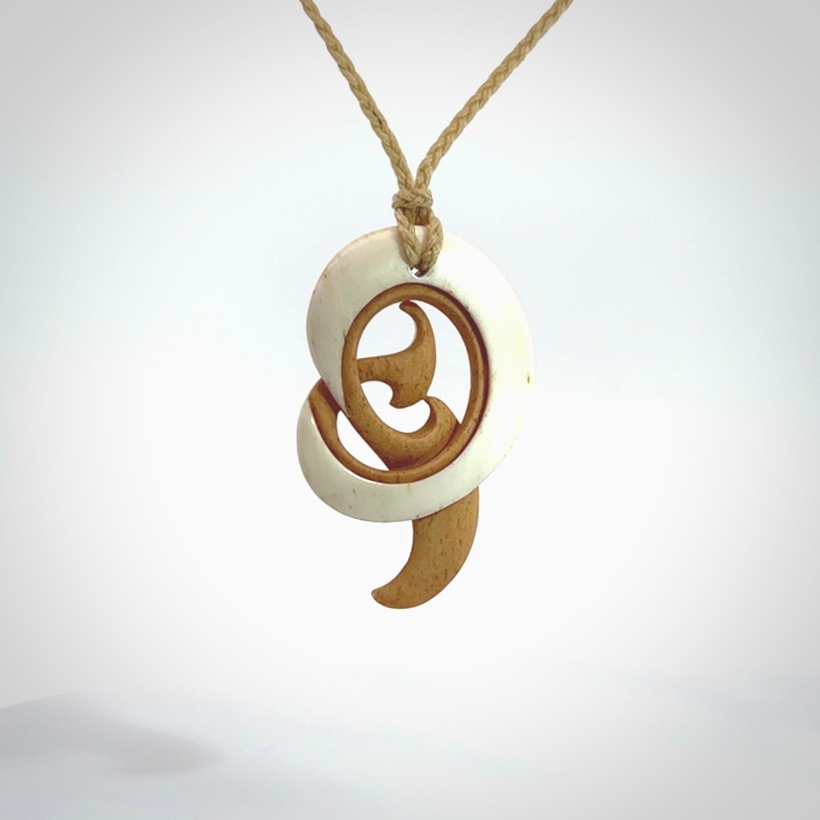 A hand carved bone contemporary, intricate pendant. The cord is a oat colour and is a adjustable in length. A medium sized hand made contemporary necklace by New Zealand artist Kerry Thompson. Kerry has stained parts of the bone which really add to the dimension of this pendant. One off work of art to wear.