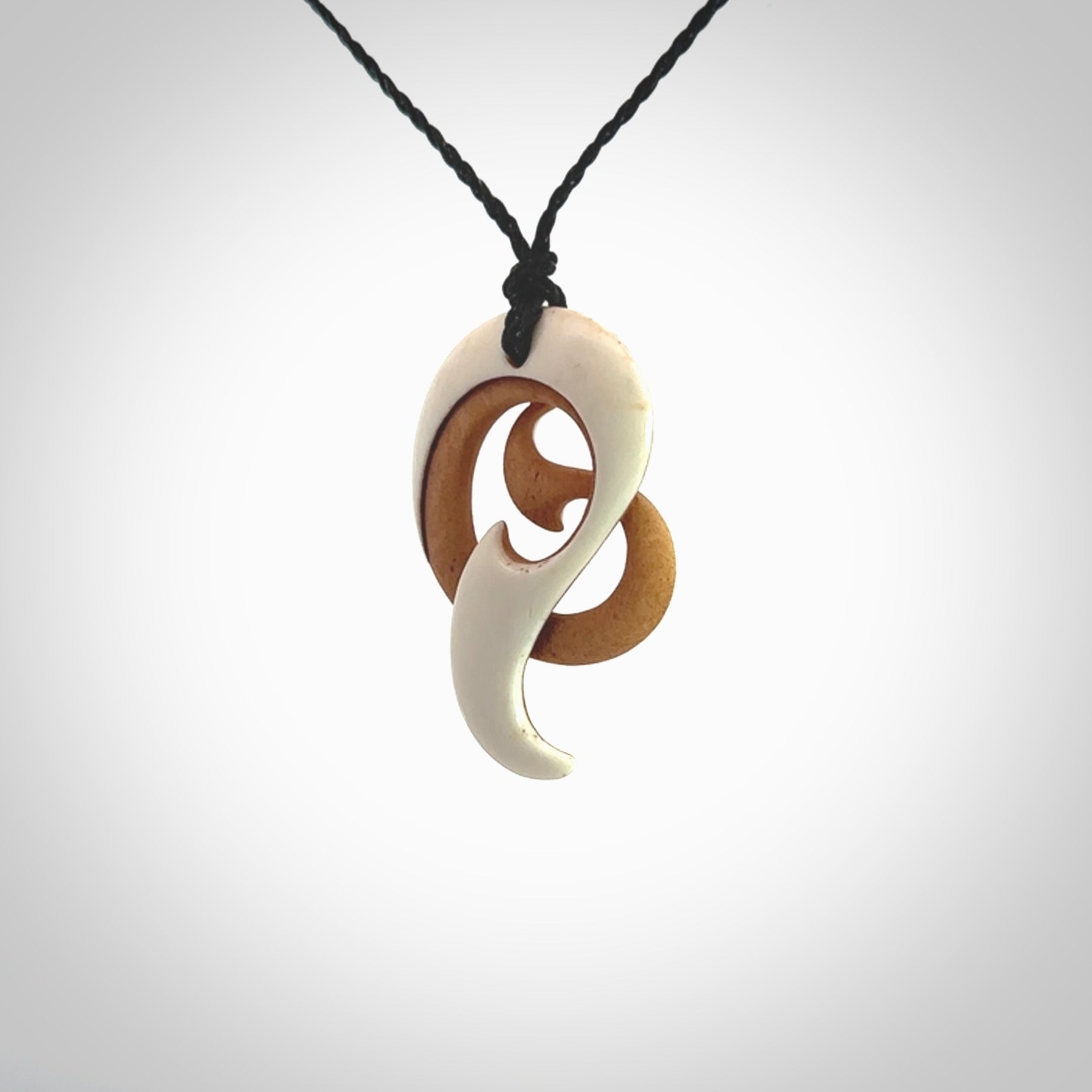 A hand carved bone contemporary, intricate pendant. The cord is a black colour and is a adjustable in length. A medium sized hand made contemporary necklace by New Zealand artist Kerry Thompson. Kerry has stained parts of the bone which really add to the dimension of this pendant. One off work of art to wear.