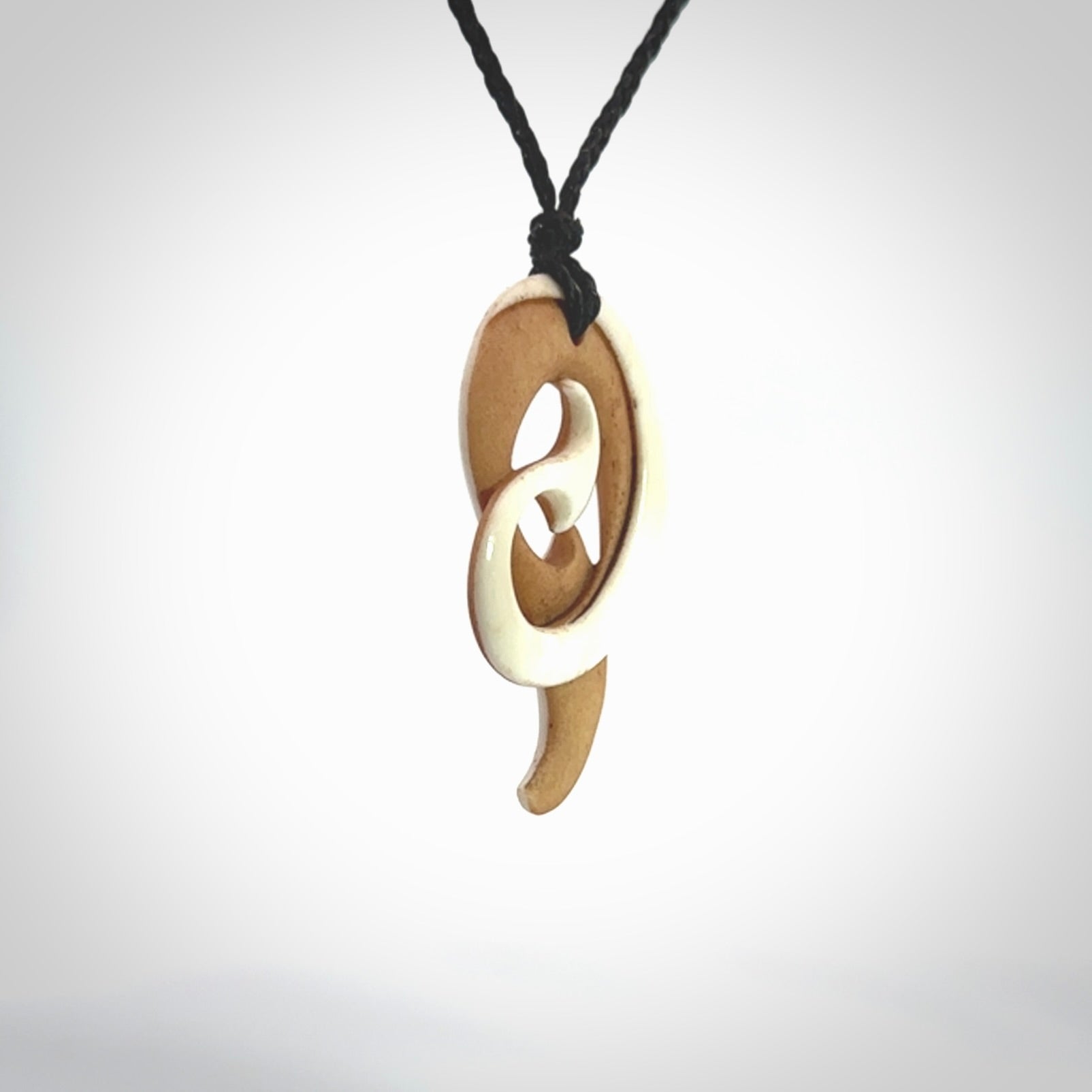 A hand carved bone contemporary, intricate pendant. The cord is a black colour and is a adjustable in length. A medium sized hand made contemporary necklace by New Zealand artist Kerry Thompson. Kerry has stained parts of the bone which really add to the dimension of this pendant. One off work of art to wear.