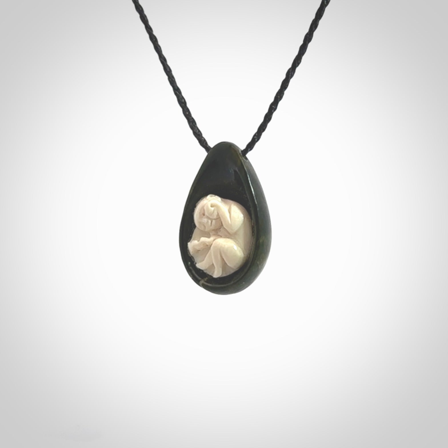 A hand carved baby in the womb pendant made from a jade and bone. This is a work of art carved in jade and bone. We deliver this pendant to you on a plaited cord. Delivery with Express Courier is included in the price.