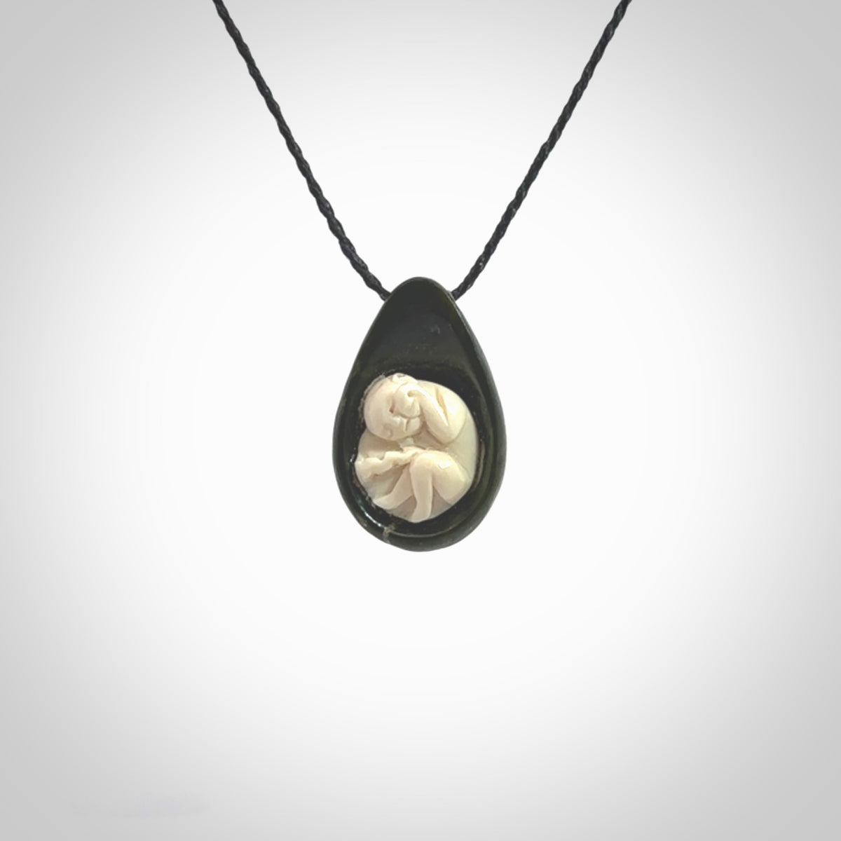 A hand carved baby in the womb pendant made from a jade and bone. This is a work of art carved in jade and bone. We deliver this pendant to you on a plaited cord. Delivery with Express Courier is included in the price.