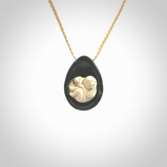 A hand carved baby in the womb pendant made from a jade and bone. This is a work of art carved in jade and bone. We deliver this pendant to you on a plaited cord. Delivery with Express Courier is included in the price.