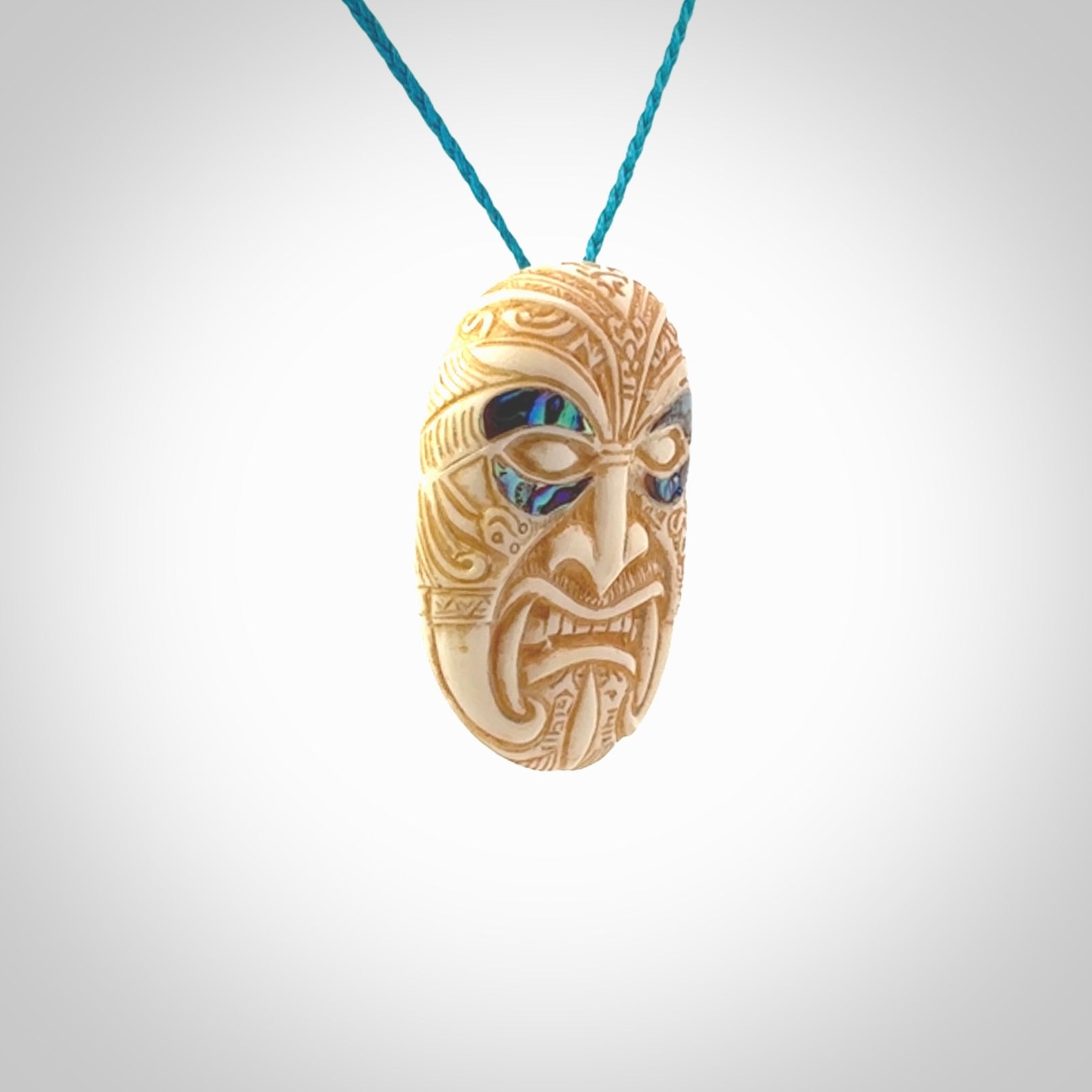 This picture shows a hand carved face pendant. It is carved from bone with paua shell and although a medium piece, it is a wonderful, delicate piece of jewellery. The cord is hand plaited and adjustable so that you can position the pendant where it suits you best. Delivery is free worldwide.