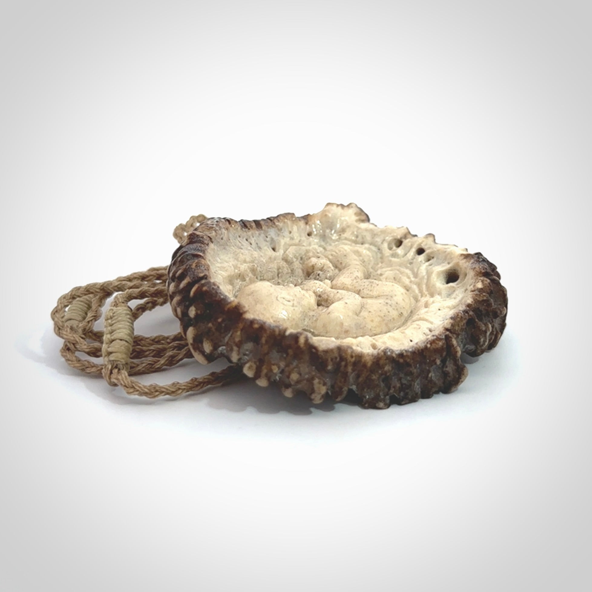 A hand carved baby in the womb pendant made from a piece of deer antler crown. This is a work of art carved in deer antler, bone. We deliver this pendant to you on a plaited tan cord. Delivery with Express Courier is included in the price.