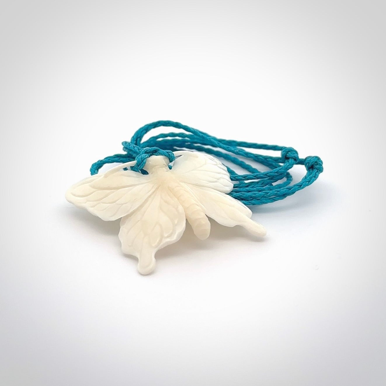 Medium sized Butterfly design pendant carved in natural bone. Real bone jewellery for sale online with NZ Pacific. Medium butterfly pendant hand made in bone, provided with paradise blue cord and packaged in a woven kete pouch.