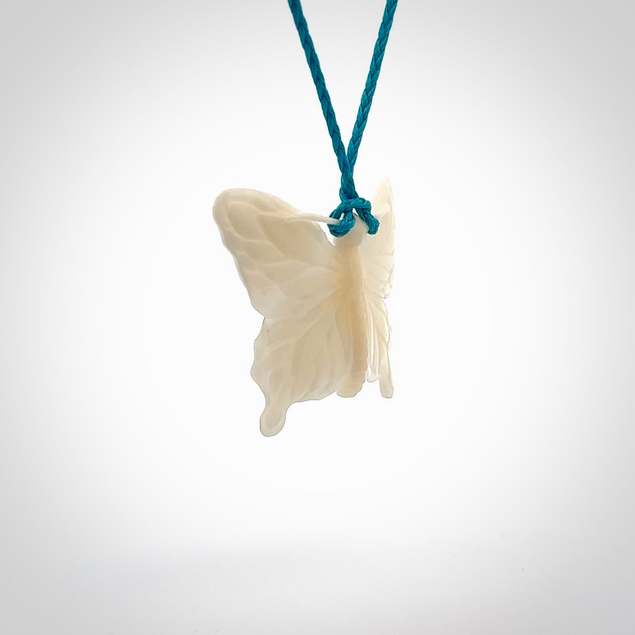 Medium sized Butterfly design pendant carved in natural bone. Real bone jewellery for sale online with NZ Pacific. Medium butterfly pendant hand made in bone, provided with paradise blue cord and packaged in a woven kete pouch.