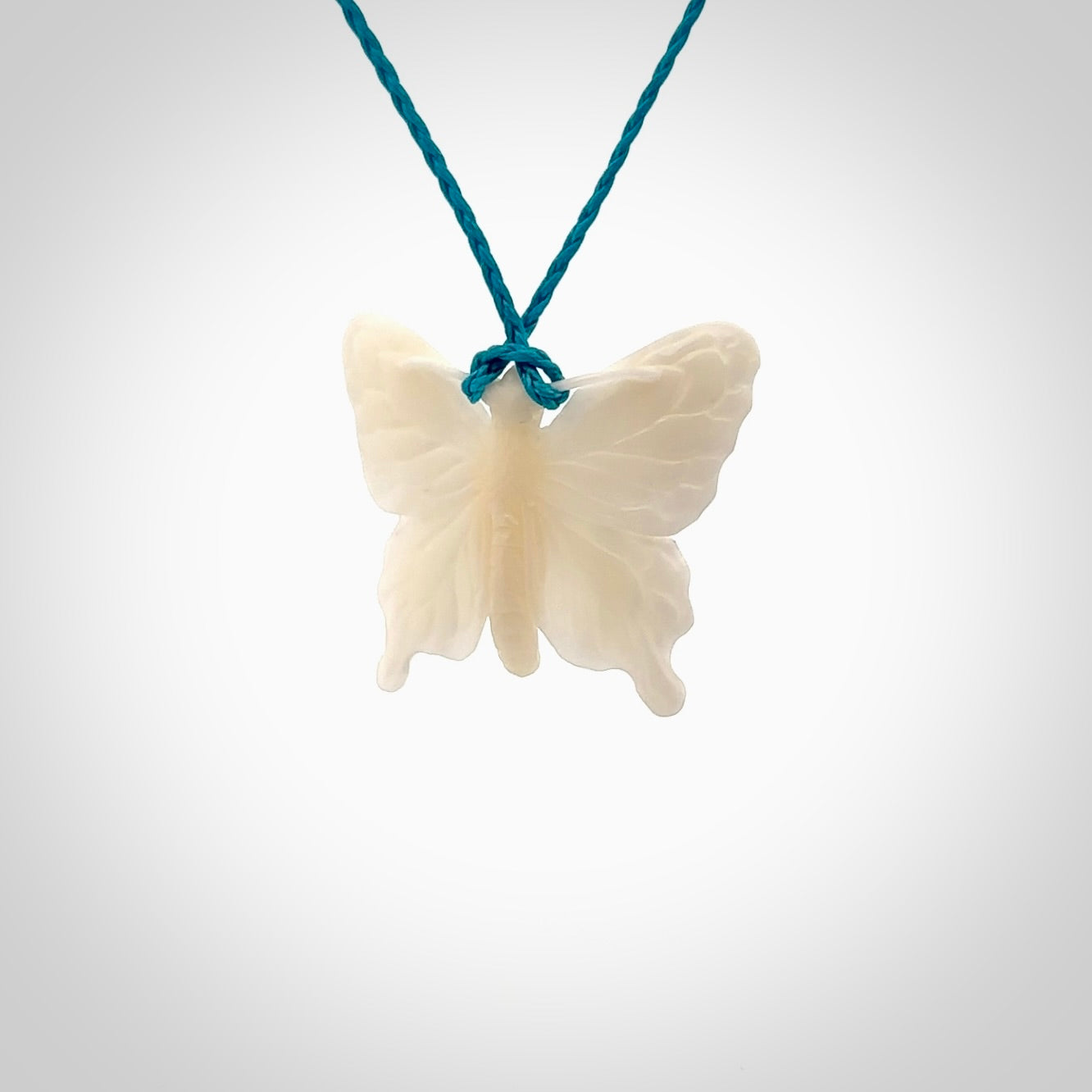 Medium sized Butterfly design pendant carved in natural bone. Real bone jewellery for sale online with NZ Pacific. Medium butterfly pendant hand made in bone, provided with paradise blue cord and packaged in a woven kete pouch.