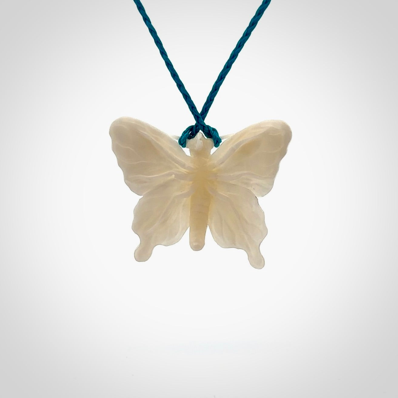 Medium sized Butterfly design pendant carved in natural bone. Real bone jewellery for sale online with NZ Pacific. Medium butterfly pendant hand made in bone, provided with paradise blue cord and packaged in a woven kete pouch.