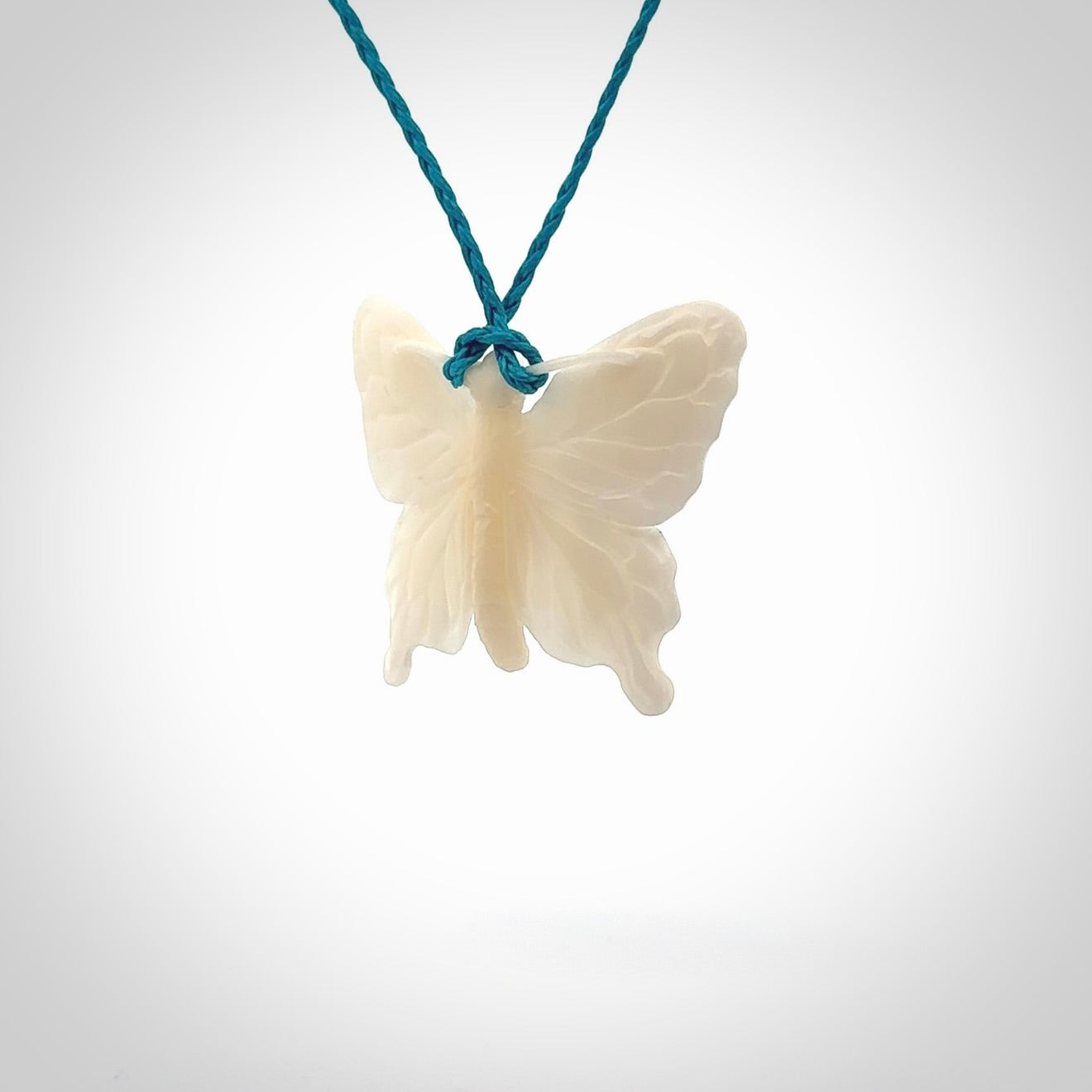 Medium sized Butterfly design pendant carved in natural bone. Real bone jewellery for sale online with NZ Pacific. Medium butterfly pendant hand made in bone, provided with paradise blue cord and packaged in a woven kete pouch.