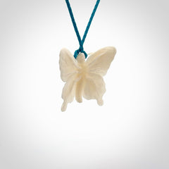 Medium sized Butterfly design pendant carved in natural bone. Real bone jewellery for sale online with NZ Pacific. Medium butterfly pendant hand made in bone, provided with paradise blue cord and packaged in a woven kete pouch.