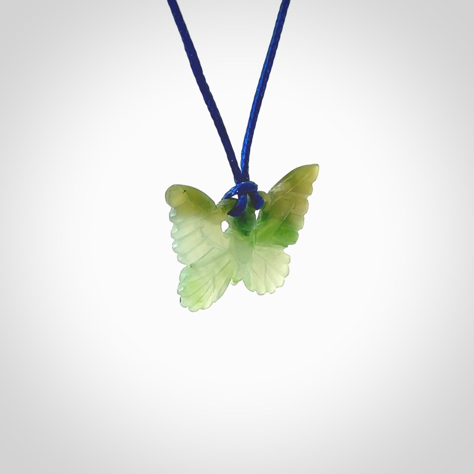 Small Butterfly design pendant carved in nephrite jade. Real jade jewellery for sale online with NZ Pacific. Small butterfly pendant hand made in Jade, provided with pacific blue cord and packaged in a woven kete pouch.