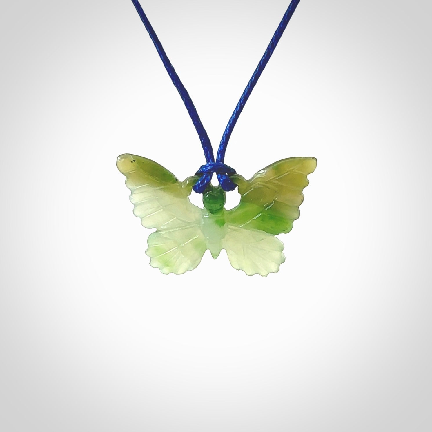 Small Butterfly design pendant carved in nephrite jade. Real jade jewellery for sale online with NZ Pacific. Small butterfly pendant hand made in Jade, provided with pacific blue cord and packaged in a woven kete pouch.