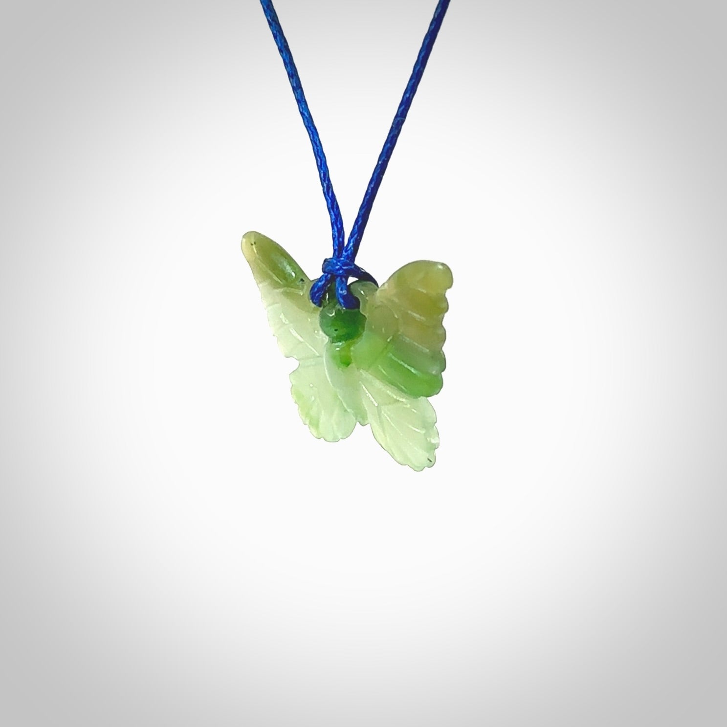 Small Butterfly design pendant carved in nephrite jade. Real jade jewellery for sale online with NZ Pacific. Small butterfly pendant hand made in Jade, provided with pacific blue cord and packaged in a woven kete pouch.