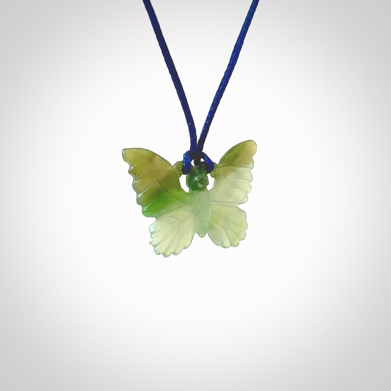 Small Butterfly design pendant carved in nephrite jade. Real jade jewellery for sale online with NZ Pacific. Small butterfly pendant hand made in Jade, provided with pacific blue cord and packaged in a woven kete pouch.