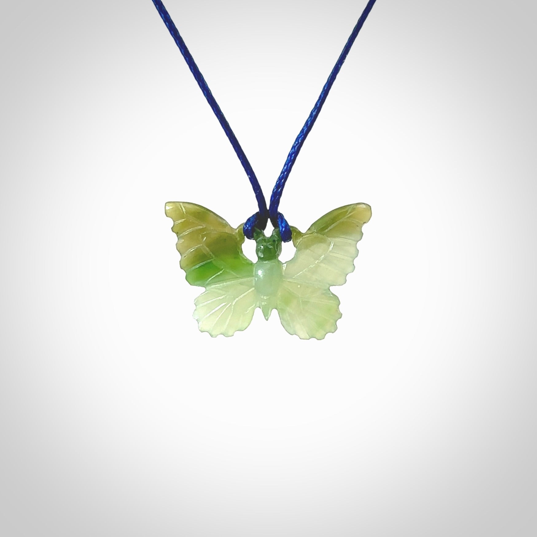 Small Butterfly design pendant carved in nephrite jade. Real jade jewellery for sale online with NZ Pacific. Small butterfly pendant hand made in Jade, provided with pacific blue cord and packaged in a woven kete pouch.