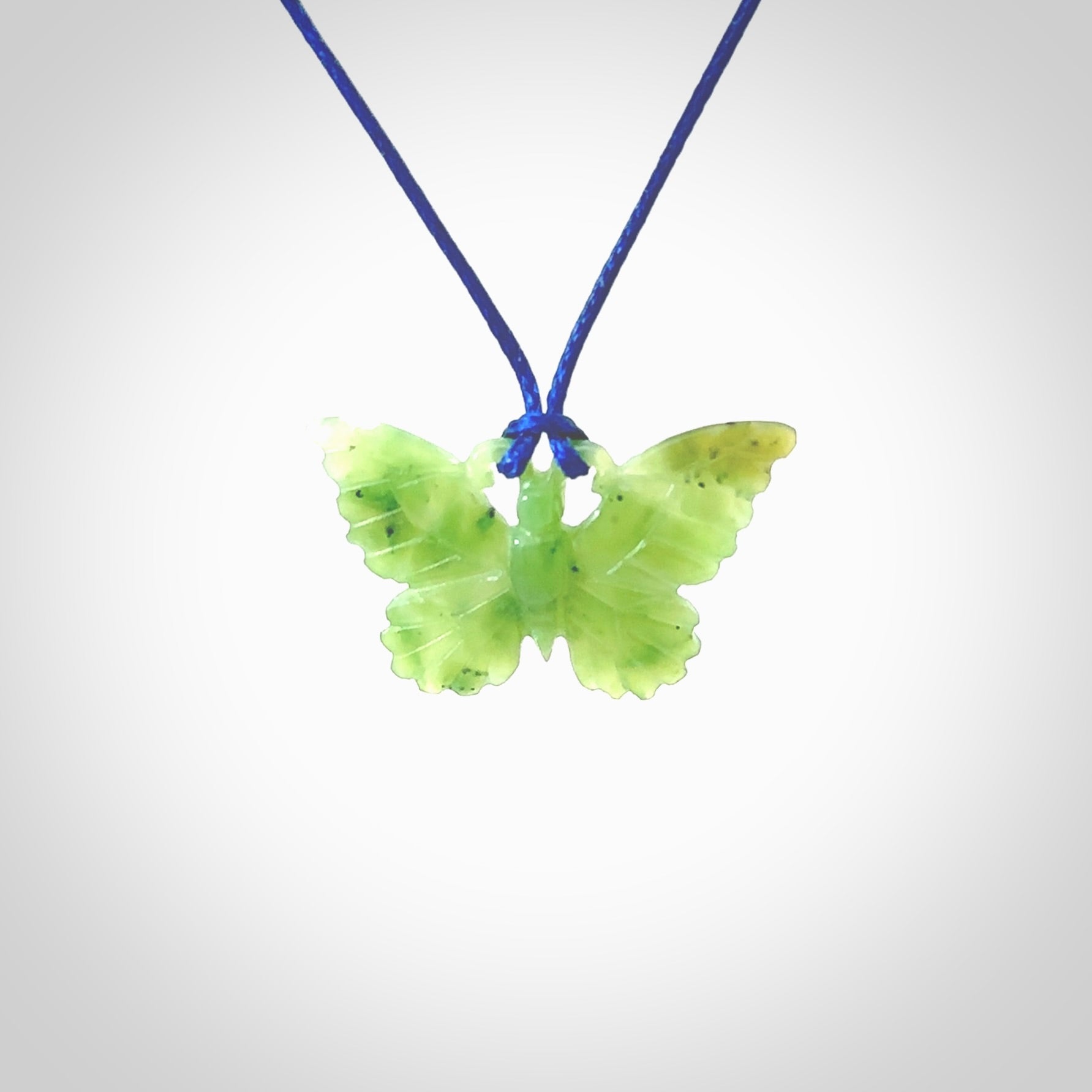 Small Butterfly design pendant carved in nephrite jade. Real jade jewellery for sale online with NZ Pacific. Small butterfly pendant hand made in Jade, provided with pacific blue cord and packaged in a woven kete pouch.