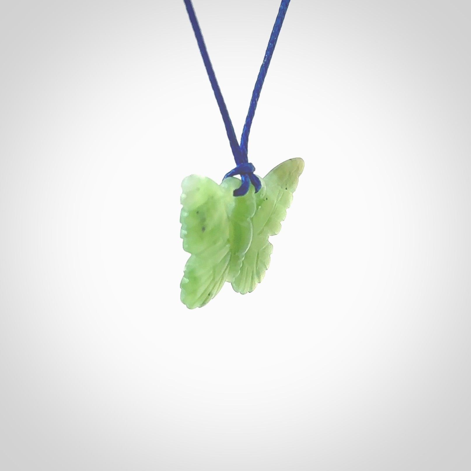 Small Butterfly design pendant carved in nephrite jade. Real jade jewellery for sale online with NZ Pacific. Small butterfly pendant hand made in Jade, provided with pacific blue cord and packaged in a woven kete pouch.