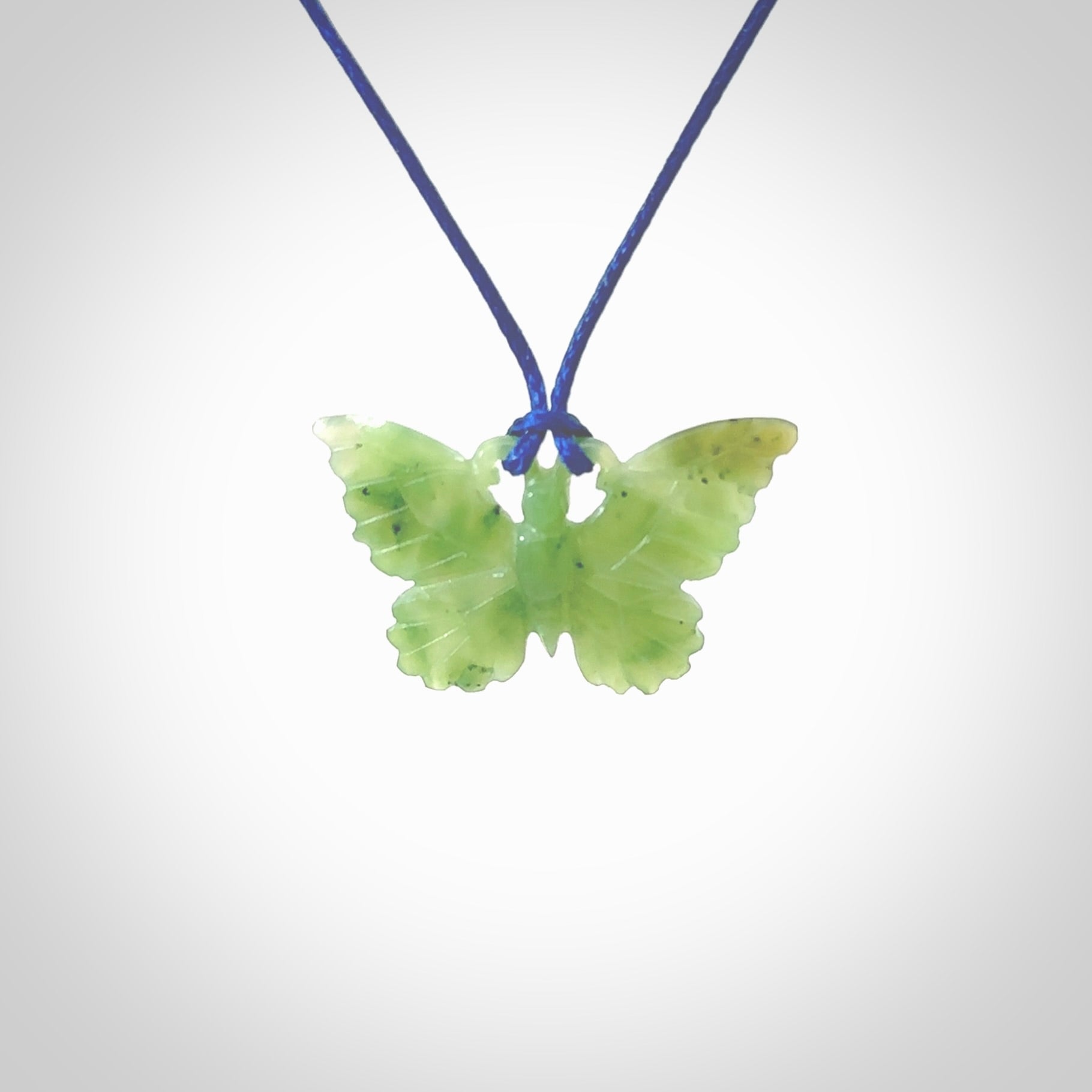 Small Butterfly design pendant carved in nephrite jade. Real jade jewellery for sale online with NZ Pacific. Small butterfly pendant hand made in Jade, provided with pacific blue cord and packaged in a woven kete pouch.