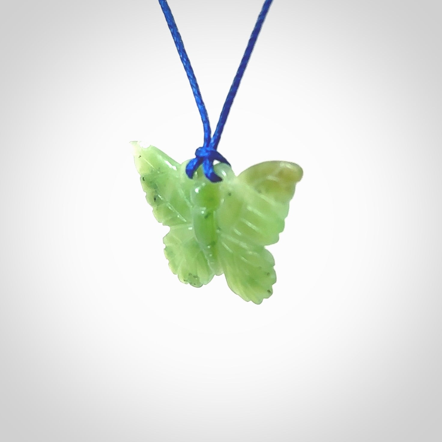 Small Butterfly design pendant carved in nephrite jade. Real jade jewellery for sale online with NZ Pacific. Small butterfly pendant hand made in Jade, provided with pacific blue cord and packaged in a woven kete pouch.