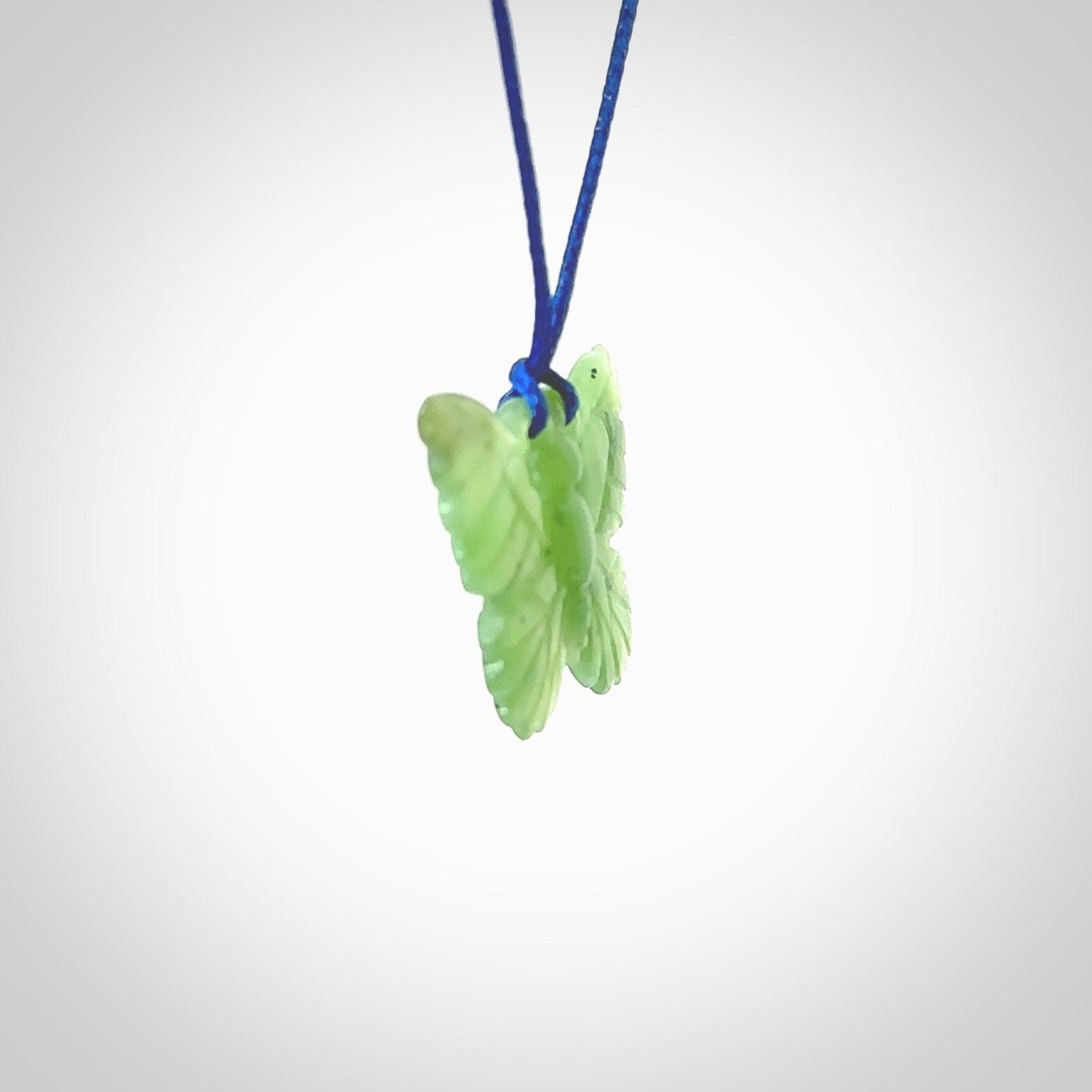 Small Butterfly design pendant carved in nephrite jade. Real jade jewellery for sale online with NZ Pacific. Small butterfly pendant hand made in Jade, provided with pacific blue cord and packaged in a woven kete pouch.