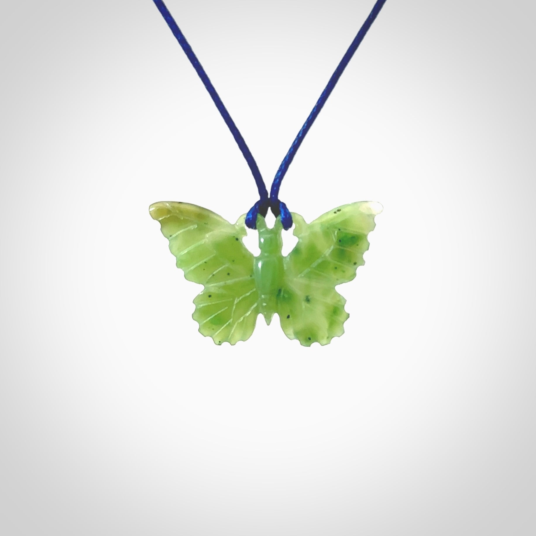 Small Butterfly design pendant carved in nephrite jade. Real jade jewellery for sale online with NZ Pacific. Small butterfly pendant hand made in Jade, provided with pacific blue cord and packaged in a woven kete pouch.