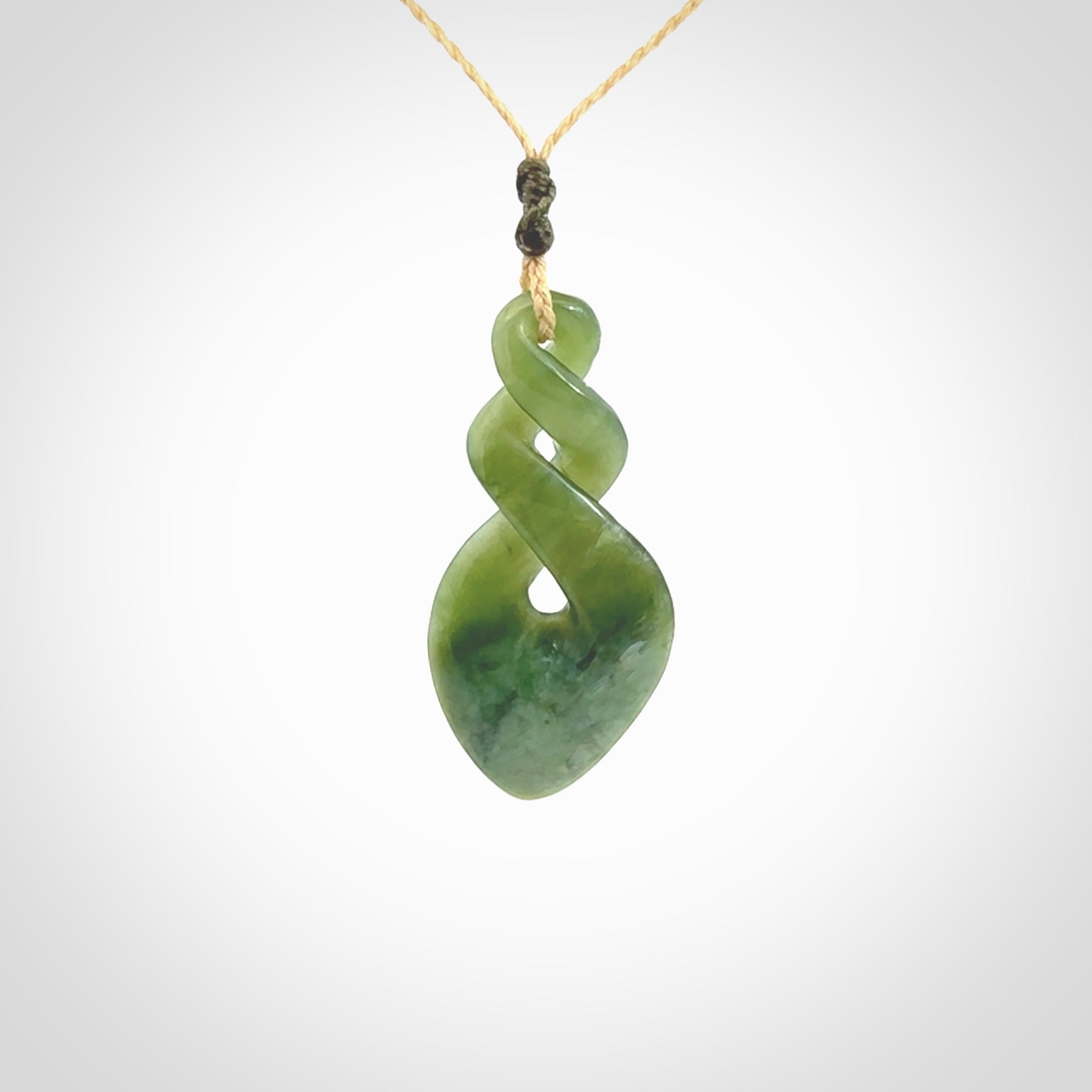 Hand carved New Zealand jade twist pendant. Carved in New Zealand by NZ Pacific. Unique double twist jewellery for sale online. Provided with an adjustable oat coloured cord.