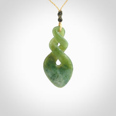 Hand carved New Zealand jade twist pendant. Carved in New Zealand by NZ Pacific. Unique double twist jewellery for sale online. Provided with an adjustable oat coloured cord.