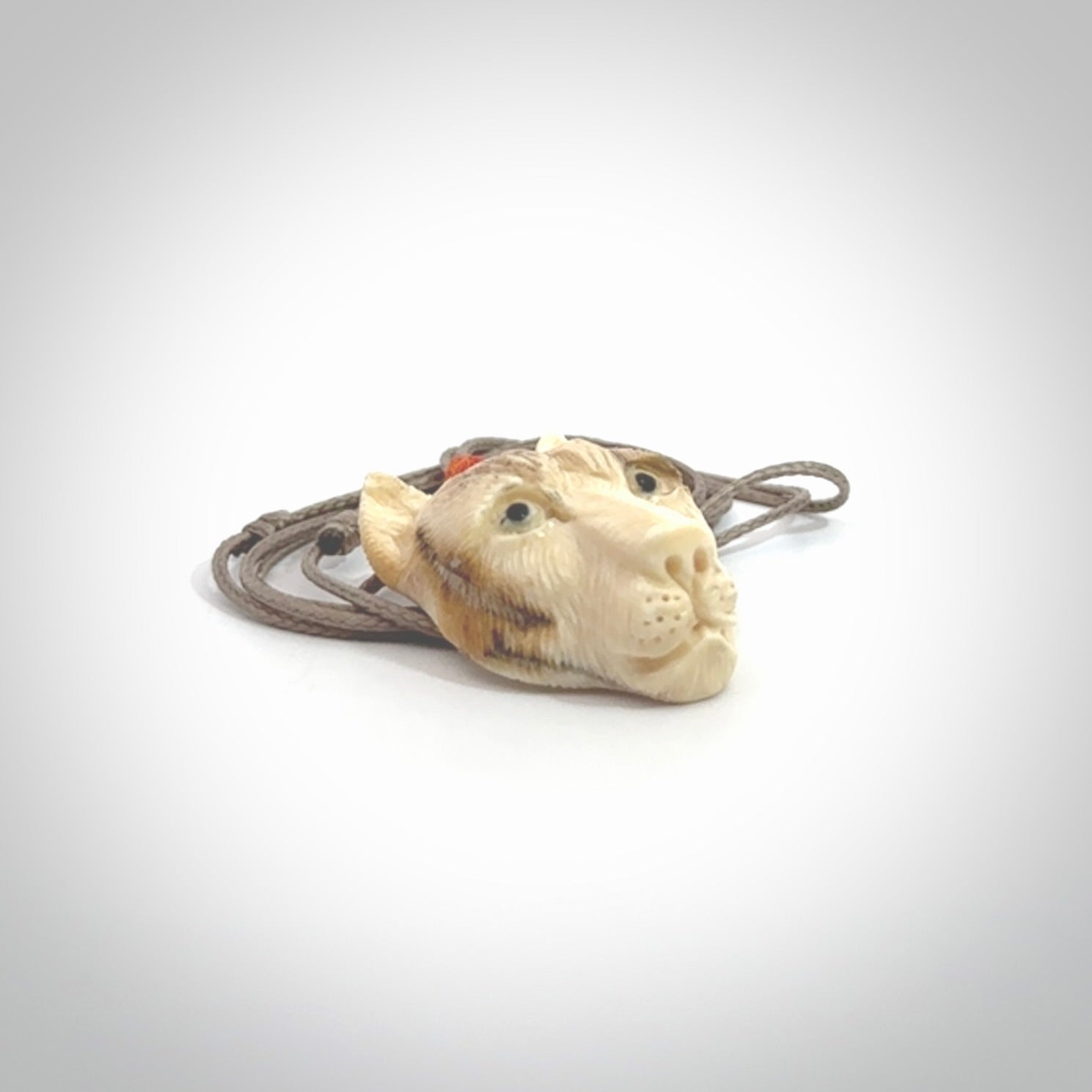 This pendant is a hand carved puma. We've carved this from a lovely piece of woolly mammoth tusk and we provide it with a hand plaited cord. Shipping is free worldwide.