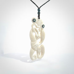 Hand carved bone Tiki pendant. Traditional art hand carved for NZ Pacific. Bone Tiki necklace with Paua Shell eyes. Delivered with Express Courier. Provided with adjustable cords and packaged in a woven kete pouch.