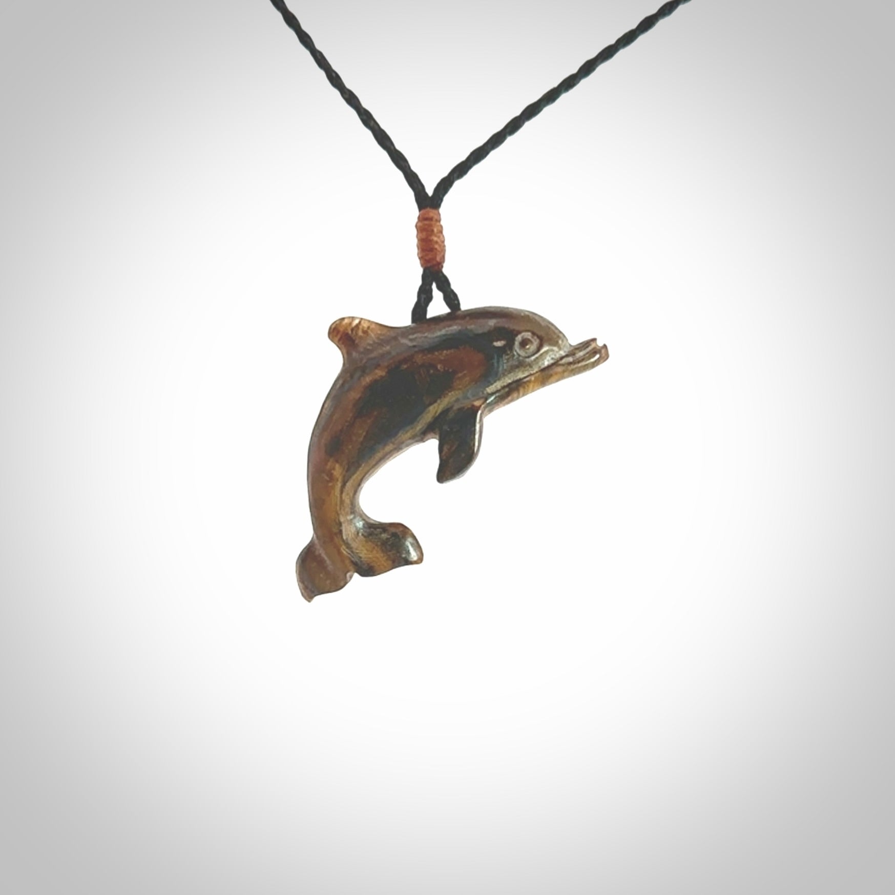 This is a hand carved dolphin pendant made from a gorgeous and striking piece of Tiger Iron. This is a superbly carved and very unique dolphin necklace. For sale online from NZ Pacific. Delivered with adjustable cord.