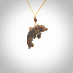 This is a hand carved dolphin pendant made from a gorgeous and striking piece of Tiger Iron. This is a superbly carved and very unique dolphin necklace. For sale online from NZ Pacific. Delivered with adjustable cord.