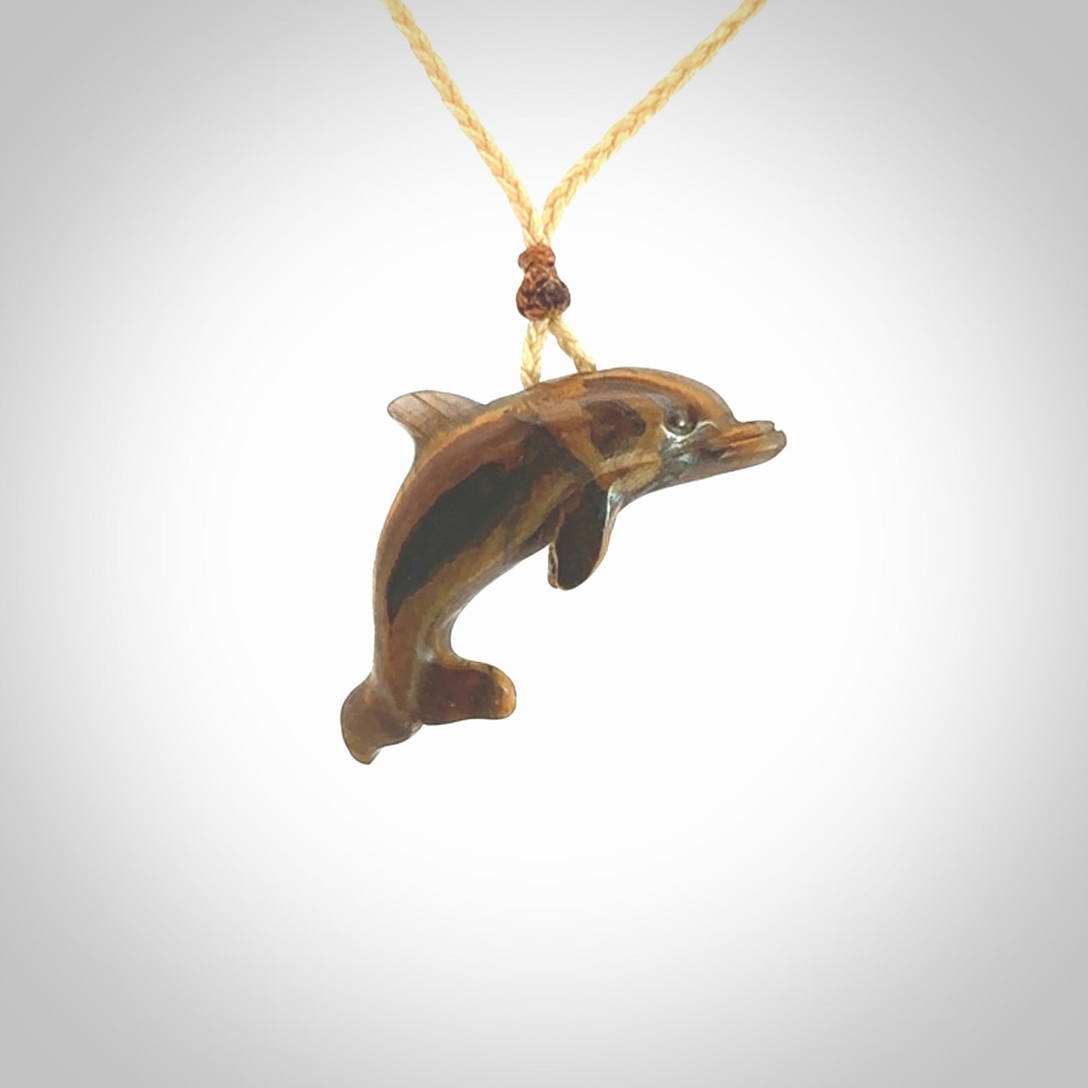 This is a hand carved dolphin pendant made from a gorgeous and striking piece of Tiger Iron. This is a superbly carved and very unique dolphin necklace. For sale online from NZ Pacific. Delivered with adjustable cord.