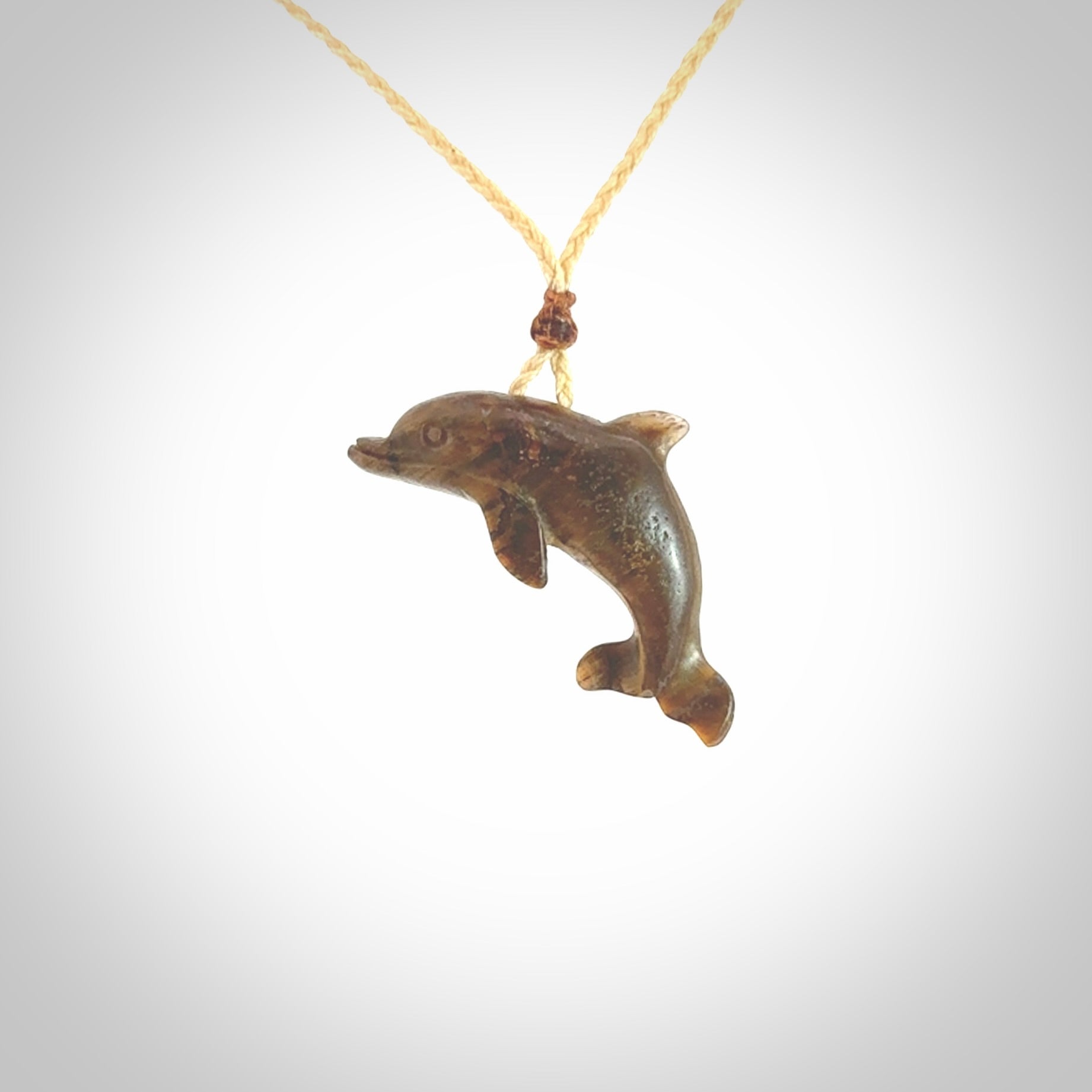 This is a hand carved dolphin pendant made from a gorgeous and striking piece of Tiger Iron. This is a superbly carved and very unique dolphin necklace. For sale online from NZ Pacific. Delivered with adjustable cord.