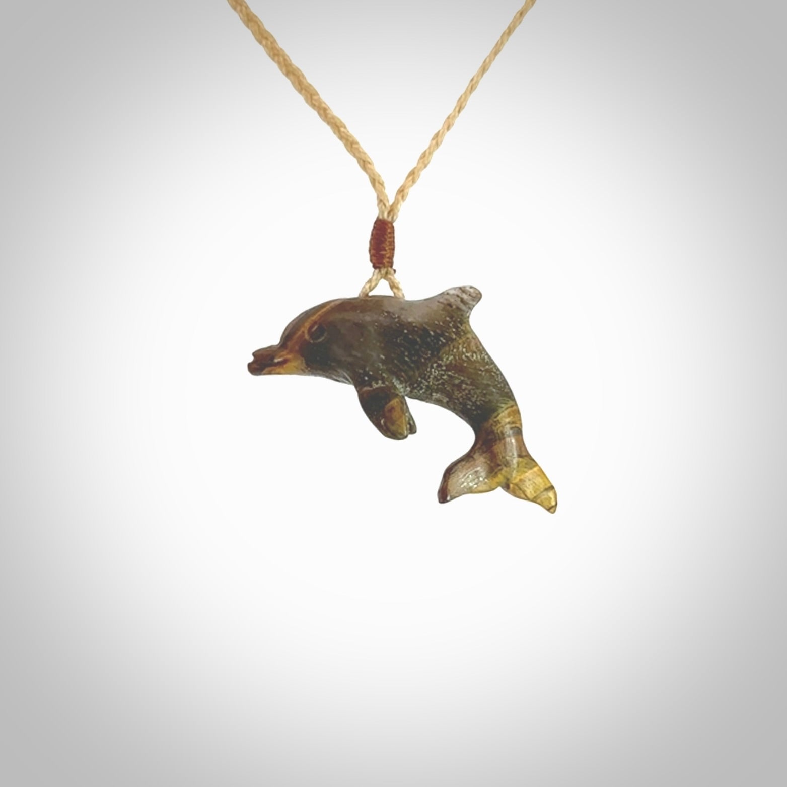 This is a hand carved dolphin pendant made from a gorgeous and striking piece of Tiger Iron. This is a superbly carved and very unique dolphin necklace. For sale online from NZ Pacific. Delivered with adjustable cord.