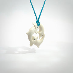 Hand carved dolphin trio pendant, made from natural bone by NZ Pacific. Hand made natural bone dolphin trilogy necklace, provided with an adjustable paradise blue cord. Packaged in a woven kete pouch.