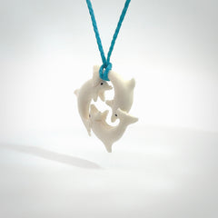 Hand carved dolphin trio pendant, made from natural bone by NZ Pacific. Hand made natural bone dolphin trilogy necklace, provided with an adjustable paradise blue cord. Packaged in a woven kete pouch.